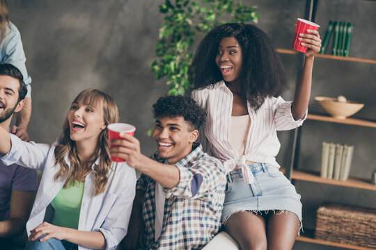 Photo of happy group of people friends party hold red cup drink good mood indoors inside house apartment