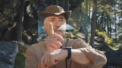 Senior Caucasian man standing in woods and using navigation app on projected AR interface on his smartwatch while hiking on summer day - Powered by Adobe