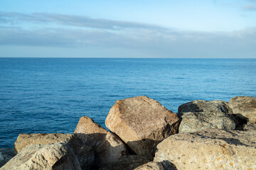 Fototapeta na wymiar Steinküste Gran Canaria bei Sonnenaufgang und ruhiger See mit leichtem Wellengang