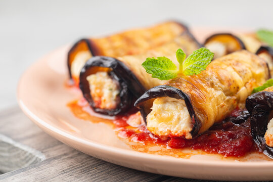Close-up of eggplant rolls with ricotta, parmesan cheese and tomato sauce. Light background.
