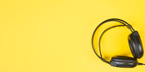 Black studio headphones on a yellow background. Banner with place for text. Flat lay, copy space.