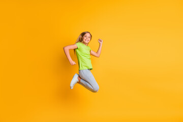 Obraz premium Full size profile side photo of young girl happy smile rejoice win victory jump up isolated over yellow color background