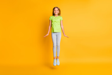 Fototapeta na wymiar Full length photo of young excited school girl happy positive smile active jump up isolated over yellow color background