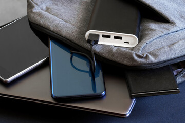 Modern gadgets - two smartphones, tablet and laptop or ultrabook lie in a gray city backpack next...