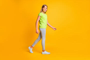 Full body profile side photo of young attractive girl happy positive smile go walk isolated over yellow color background