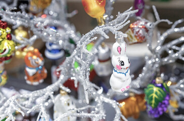 Glass Christmas tree toy in the shape of a hare on a silvery branch.