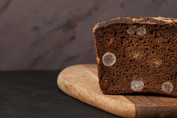 Expired rye bread with mold on cutting board, close-up. Selective focus, copy space. Appearance of mold indicates naturalness of product. Concept - reduction of organic food waste
