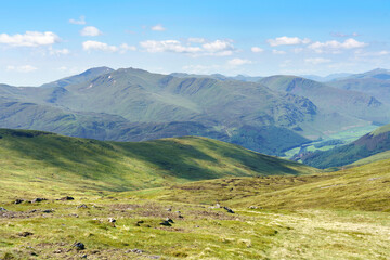 Fototapeta na wymiar Distant views of the mountain summits of Meall Garbh, Ben Lawers, Beinn Ghlas and Meall Corranaich from below the top of Carn Mairg with Glen Lyon below in the Scottish Highlands, UK landscapes.