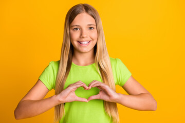 Photo of young preteen girl happy positive smile show heart figure love valentine day isolated over yellow color background