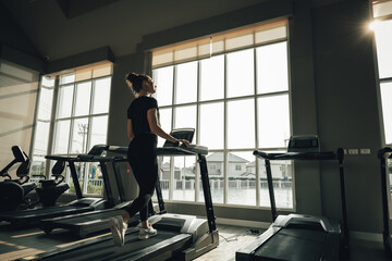 silhouette young sports woman working out and running on treadmill in gym