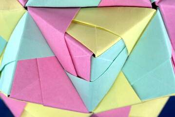 Self-made colorful origami star cube with blue background, close up.