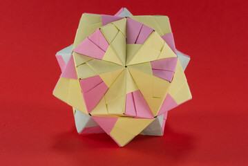 Self-made colorful origami star cube with red background.
