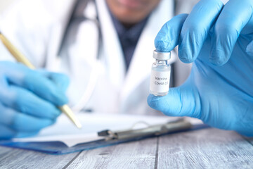 hand in latex gloves holding glass ampoule vaccine, with copy space 
