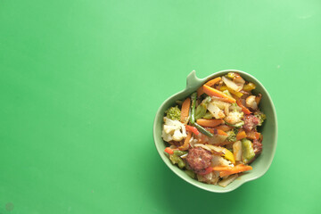 top view of homemade vegetable salad in bowl on green background 