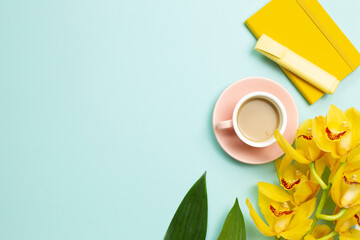 Yellow notebook, pen, cup of coffee, yellow flowers on blue background. flat lay, top view, copy...