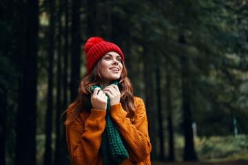 Happy woman in autumn sweater on the nature in the forest and a red hat 