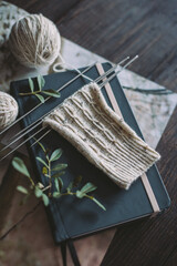 Hand knitting sock with needles and yarn balls ion a dark wooden background.