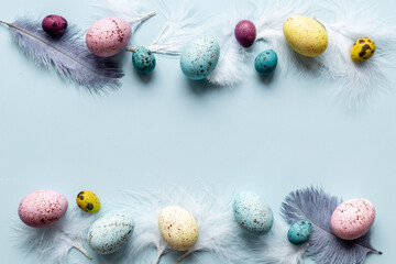 Layout of colorful Easter eggs and birds feather, top view