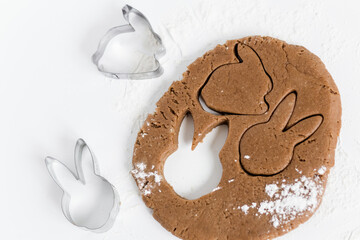 Raw easter gingerbread dough with cutters and flour. Preparation of Easter cookies. White background. Top view
