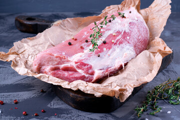 Raw pork neck meat with salt, pepper and thyme on the piece of parchment paper. Farm product