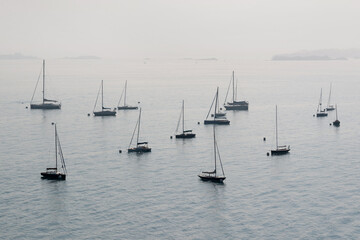 Fototapeta premium Silhouettes of anchored sailing boats in the mist
