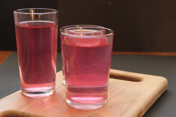Homemade mors juice compote red pink from alina strawberry blueberries in glasses stand on a board tray on a black background with a place for text and copyspace © Кристина Шоба