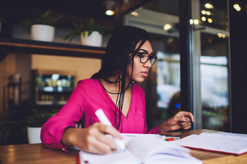 Focused black female student preparing for exam in cafe