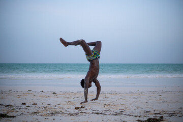 Fototapeta na wymiar Young Attractive Muscular and Strong Athletic Black African Man at the White Sand Beach Training Body Calisthenics