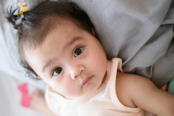 Portrait of cute little Asian baby girl lying on the bed and looking at the camera