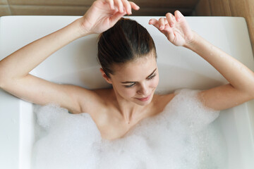 Woman in bathtub with white foam top view clean skin cosmetology 