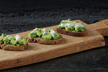 Close-up view of sandwiches with avocado spread on bread slices with tahini and yoghurt dressing.
