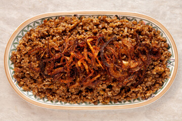 Lentil and bulgur pilaf with fried onion on the top. Palestinian cuisine.