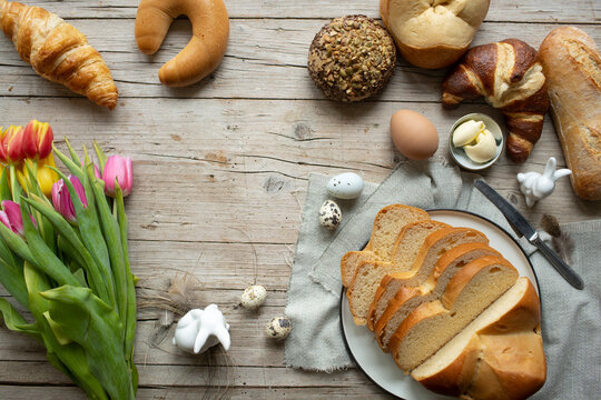 delicious fresh easter breakfast with different easter pastry and easter bread and beautiful colorful flowers tulips with decoration bunny and eggs on wooden background photo taken from above