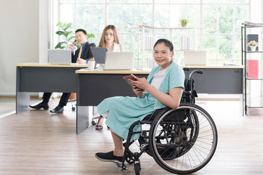 Smiling Young Asian Woman Office Worker In Wheelchair Holding Tablet Look At Camera, Disabled People Working With Colleague At Workplace
