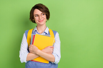Photo portrait of cheerful student keeping book pile wearing spectacles isolated vivid green color...