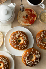 Bagels pastry buns for breakfast,with coffee cup and fruit jam. Top view, bright background, natural light.