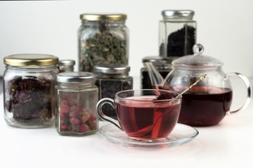 Homemade herbal tea. A remedy that boosts immunity and relieves stress. Glass teapot and tea with a healthy drink. Transparent jars with dried herbs and berries.