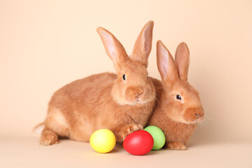 Fototapeta na wymiar Cute bunnies and Easter eggs on beige background