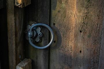 Closeup on garden door with round metal knob, wooden door with circular shape handle, old wooden fence with locked door