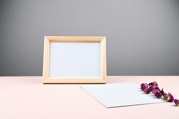 Wooden photo frame with white blank card against a gray wall. Mock up poster frame. Stylish template