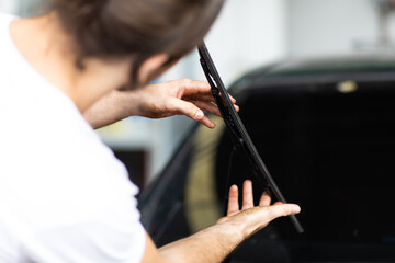 Technician and mechanical changing windscreen wipers on a car station. Car maintenance and auto service garage concept.