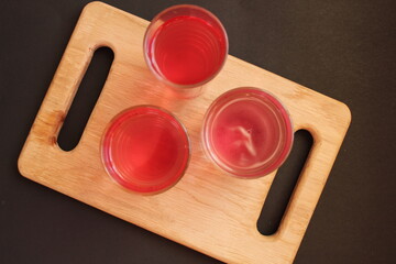 Homemade mors juice compote red pink from alina strawberry blueberries in glasses stand on a board tray on a black background with a place for text and copyspace © Кристина Шоба