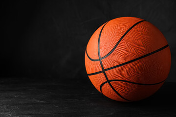 Obraz premium Orange ball on black background, space for text. Basketball equipment