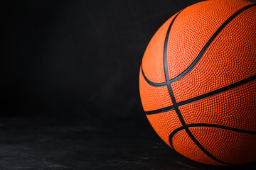 Fototapeta premium Orange ball on black background, space for text. Basketball equipment