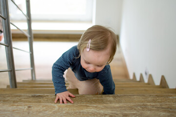 Small caucasian baby crawling on the stairs. Indoor portrait with copy space. Kid and safeness at home.