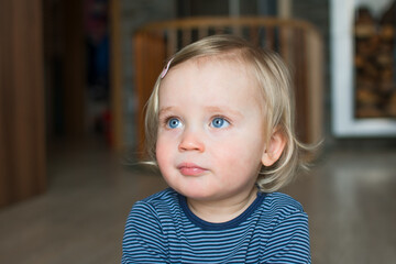 Cute caucasian baby face with blond hair and blue eyes, close up portrait. Small kid posing at...