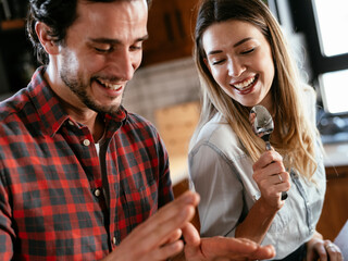 Young couple playing with kitchen utensils. Boyfriend and girlfriend having fun while preparing food
