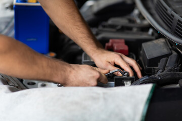 Obraz premium Auto mechanic worker checking and changing car battery. Car maintenance and auto service garage concept.