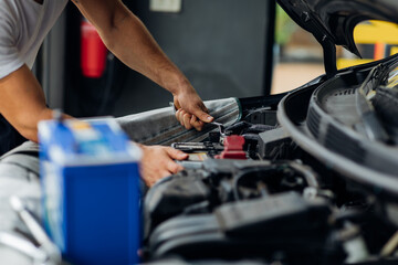 Plakat Auto mechanic worker checking and changing car battery. Car maintenance and auto service garage concept.