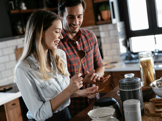 Young couple playing with kitchen utensils. Boyfriend and girlfriend having fun while preparing food